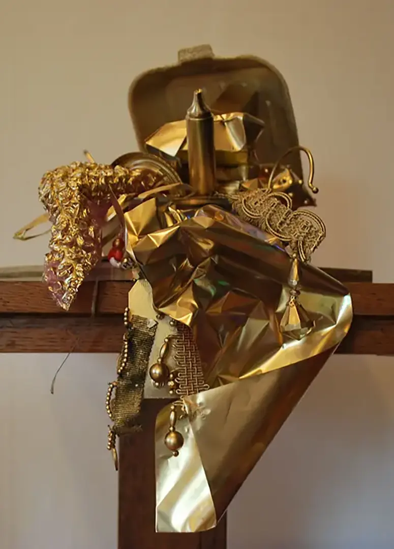 Treasure chest made out of a styrofoam takeout container and filled with trash, spray painted 
                        gold. It's sitting on a wooden pedestal and the contents are spilling over the edge.