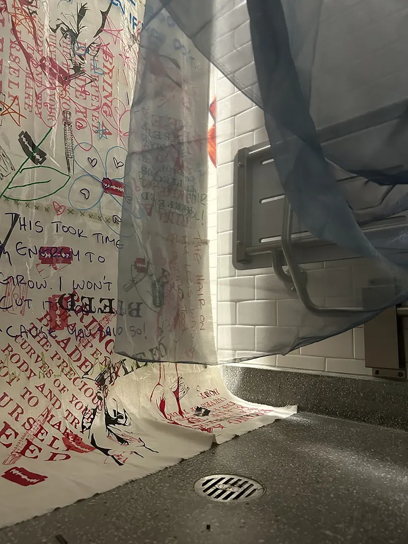 The bottom part of the curtain from inside the shower. The blue sheer fabric is draped partially 
                        in front of the camera.