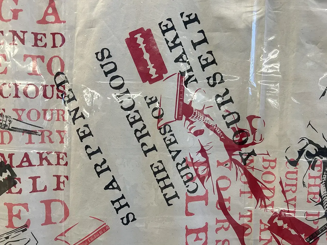 Close up of the curtain. The same text has been printed with some part removed. 
                    It reads, "sharpened the precious curves of make yourself."