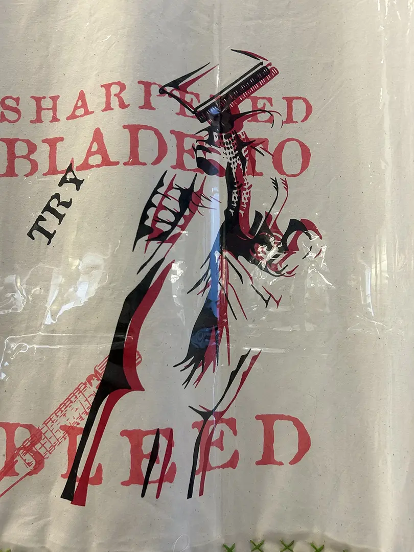 Close up of the curtain. A hand holding a razor blade has been printed over itself, 
                        slightly offset, in red and black